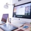 silver iMac near iPhone on brown wooden table