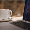 black laptop computer beside white ceramic mug close-up photography