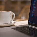 black laptop computer beside white ceramic mug close-up photography